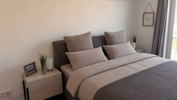 Un dormitorio con cama, mesita de noche y un cuadro colgado en la pared.
