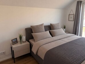 A bedroom with a bed, bedside table, and a wall-mounted picture frame. - Klabauter-Kajüte - Balcony, private parking space, washing machine, infrared cab (Olpenitz)