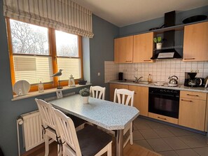A kitchen with a dining table, chairs, a stove, and a coffee maker. - Modern seaside apartment with partial sea view and family-friendly amenities (Schönberger Strand)