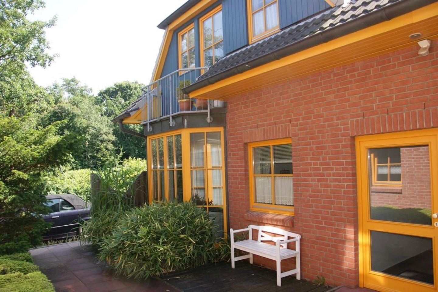 Een gebouw met twee verdiepingen, een bakstenen gevel en ramen met gele kozijnen.
