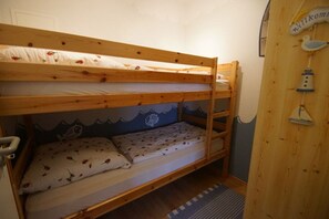 Un lit superposé avec une tête de lit décorée sur le thème de la montagne, une pancarte de bienvenue et un petit élément décoratif mural.