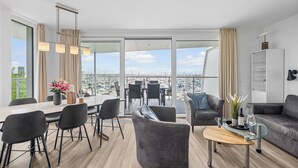 A modern living room with a dining area, a sofa, and a balcony with a city view. - Spacious Apartment with exceptional Sea View and Wellness Area! (Wendtorf)