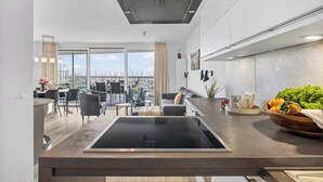 A modern kitchen with a built-in stove, a dining area with a view, and a living space with a sofa and chairs. - Spacious Apartment with exceptional Sea View and Wellness Area! (Wendtorf)