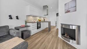 A modern kitchen with white cabinets, a central island, and a built-in fireplace. - Spacious Apartment with exceptional Sea View and Wellness Area! (Wendtorf)