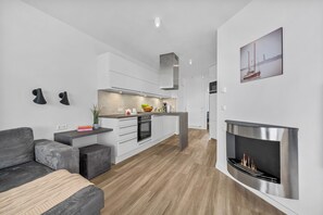 A modern kitchen with white cabinets, a central island, and a built-in fireplace. - Spacious Apartment with exceptional Sea View and Wellness Area! (Wendtorf)