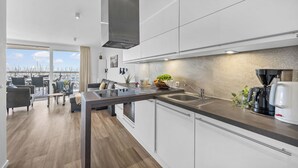 A modern kitchen with a large window, a coffee machine, and a view of the city. - Spacious Apartment with exceptional Sea View and Wellness Area! (Wendtorf)