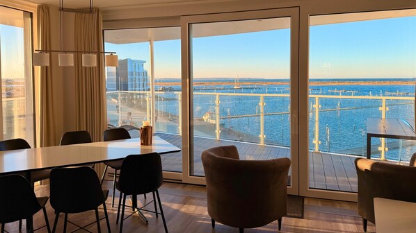 Une chambre d’hôtel moderne dotée d’une grande fenêtre donnant sur un port de plaisance.