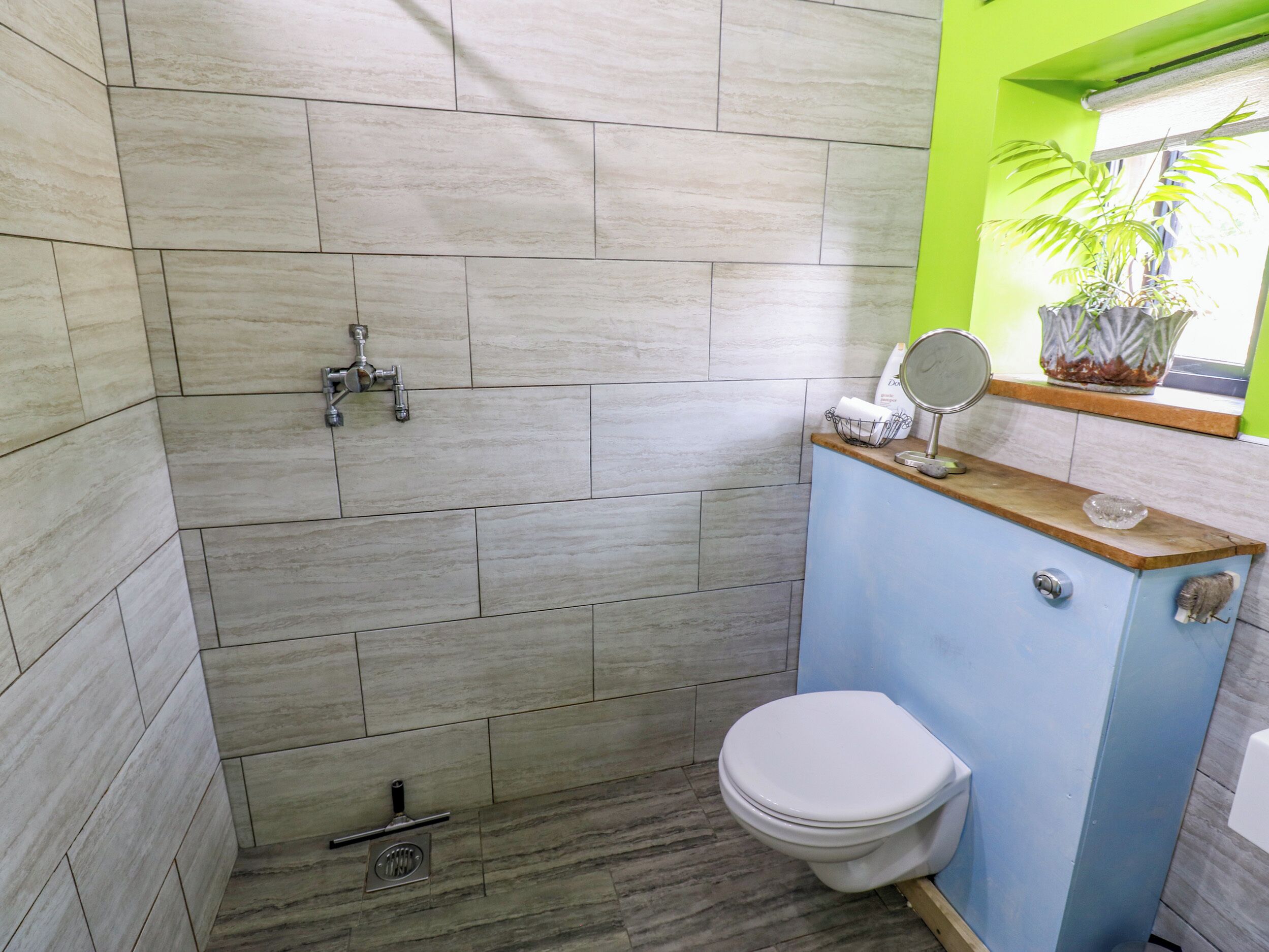 A bathroom with a shower, toilet, sink, and a mirror.