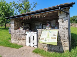 A stone-built structure with a signboard, a welcome sign, and a map. - The Brew House (Penrith)