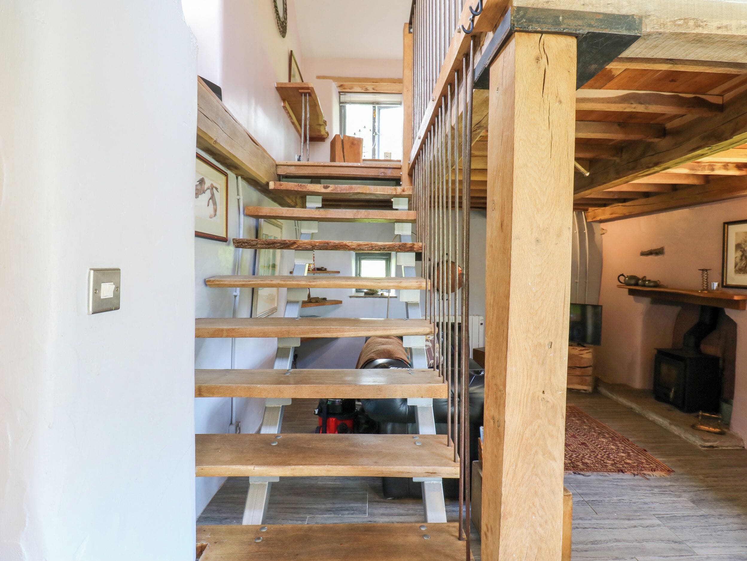 Una escalera de madera con barandillas de metal, un radiador y una chimenea en una habitación con piso de baldosas.