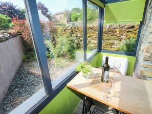 A room with a large window, a table with a bottle and glass, and a map. - The Brew House (Penrith)