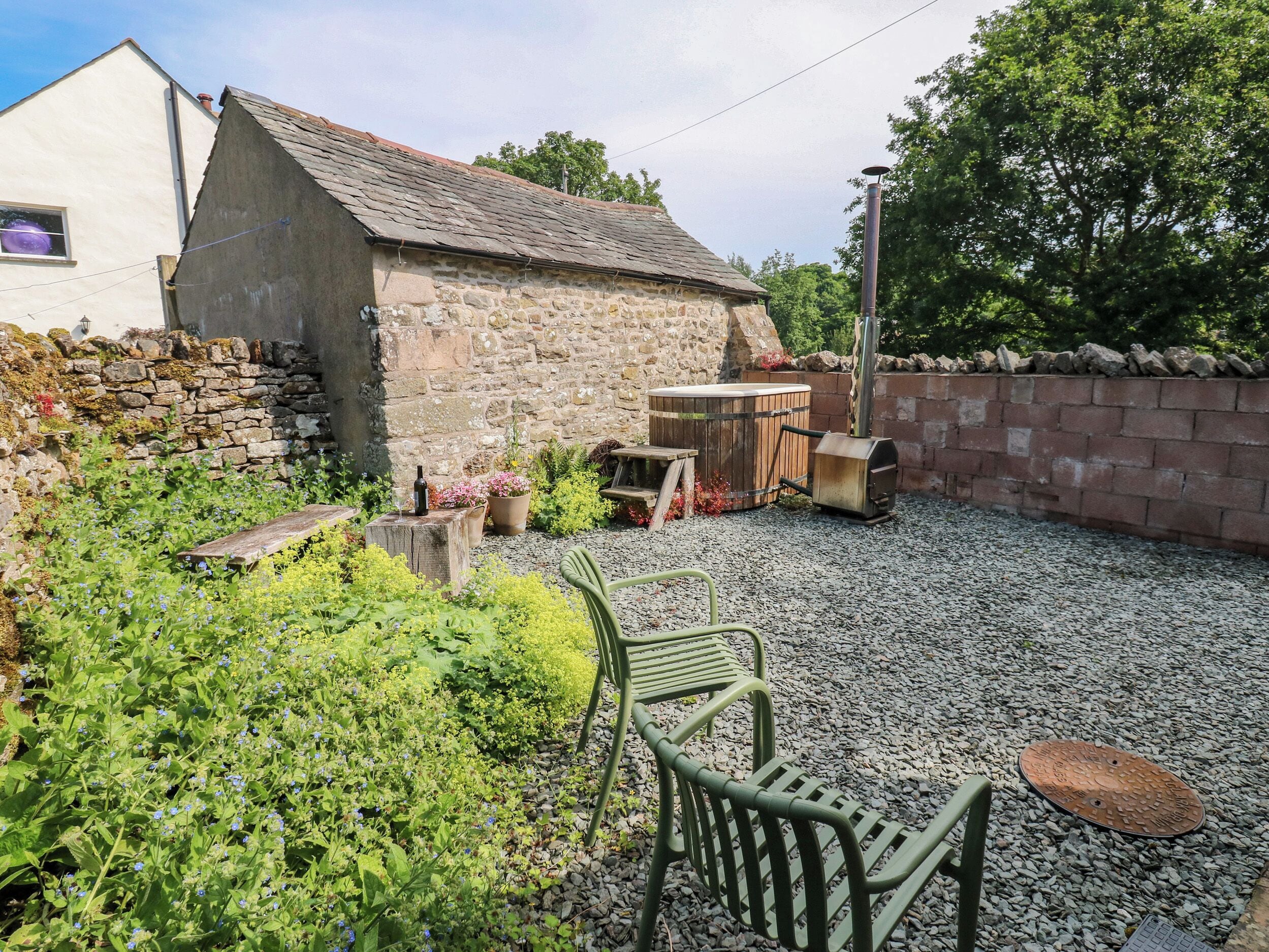 A rustic outdoor area with a stone building, a wooden barrel, and a bench.