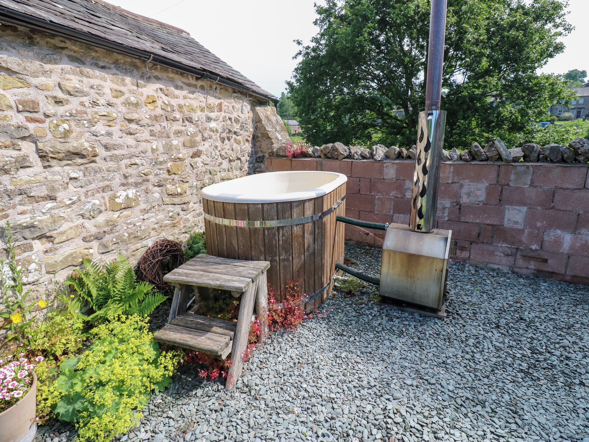 A stone building with a wooden hot tub and a step stool.