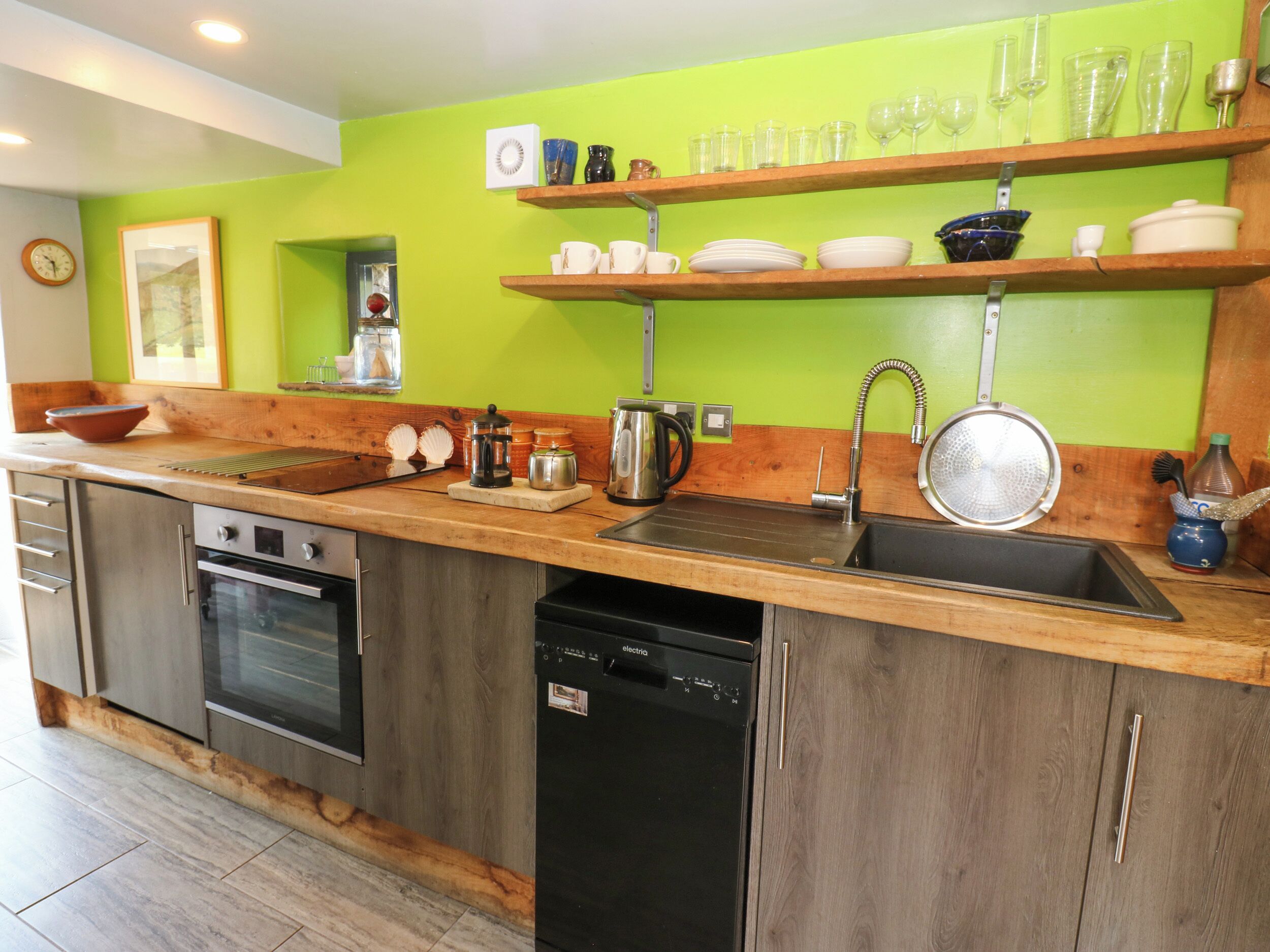 A kitchen with wooden cabinets, a dishwasher, a sink, and a green wall.