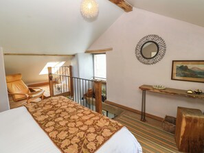 A bedroom with a bed, a chair, a small table, a mirror, and a window. - The Brew House (Penrith)