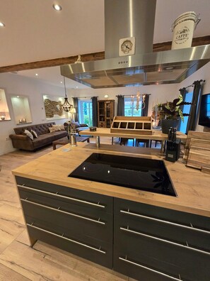 A modern kitchen with a central island, built-in cabinetry, and a stainless steel range hood.