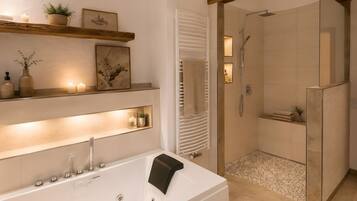 A modern bathroom with a bathtub, shower, and shelves with candles and decor.