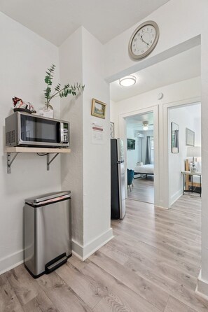 Een moderne keuken met een magnetron, koelkast en een klok aan de muur.