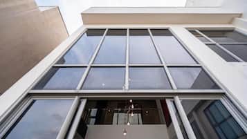 En moderne bygning med store vinduer og en balkon med hængende lys.