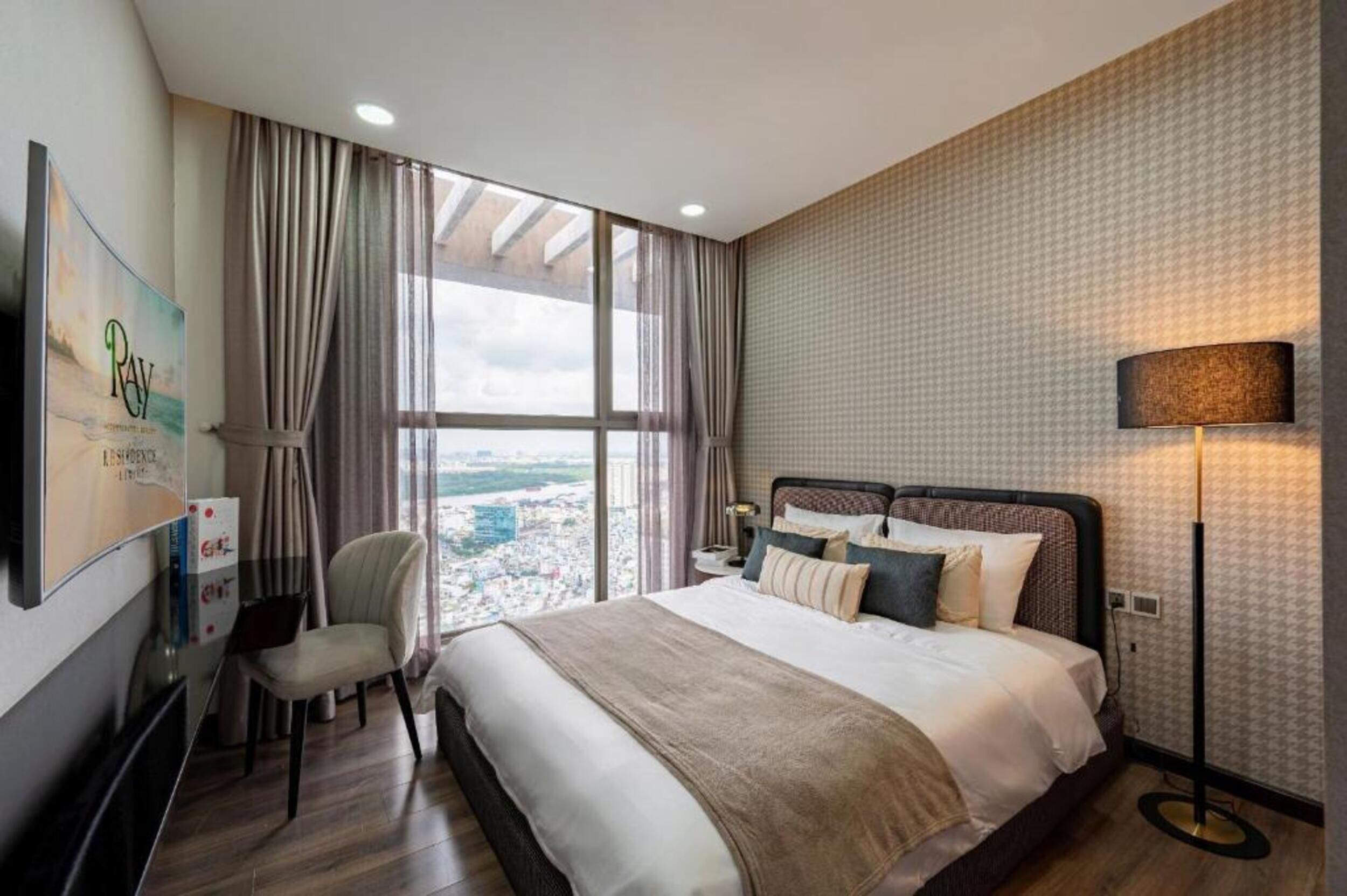 Une chambre d’hôtel avec un grand lit, une chaise, un bureau, une lampe et une vue sur la ville.