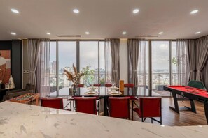 A modern living room with a pool table, red chairs, and a large window offering a city view. - Stunning Penthouse in the City Centre (Ho Chi Minh City)