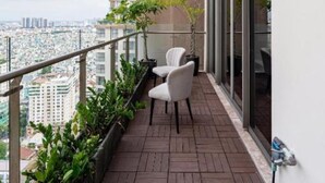 A balcony with a view of the city, a potted plant, and a chair. - Stunning Penthouse in the City Centre (Ho Chi Minh City)