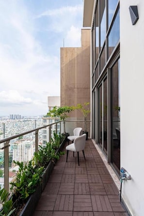 Un balcón con vistas a la ciudad, una planta en maceta y una silla.