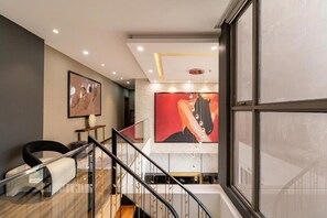 Un interior moderno con una escalera, un cuadro abstracto grande y un diseño minimalista.