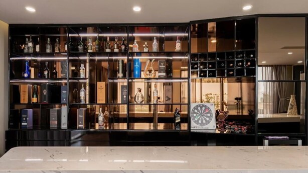A bar area with shelves of liquor bottles, a dartboard, and a marble countertop. - Stunning Penthouse in the City Centre (Ho Chi Minh City)