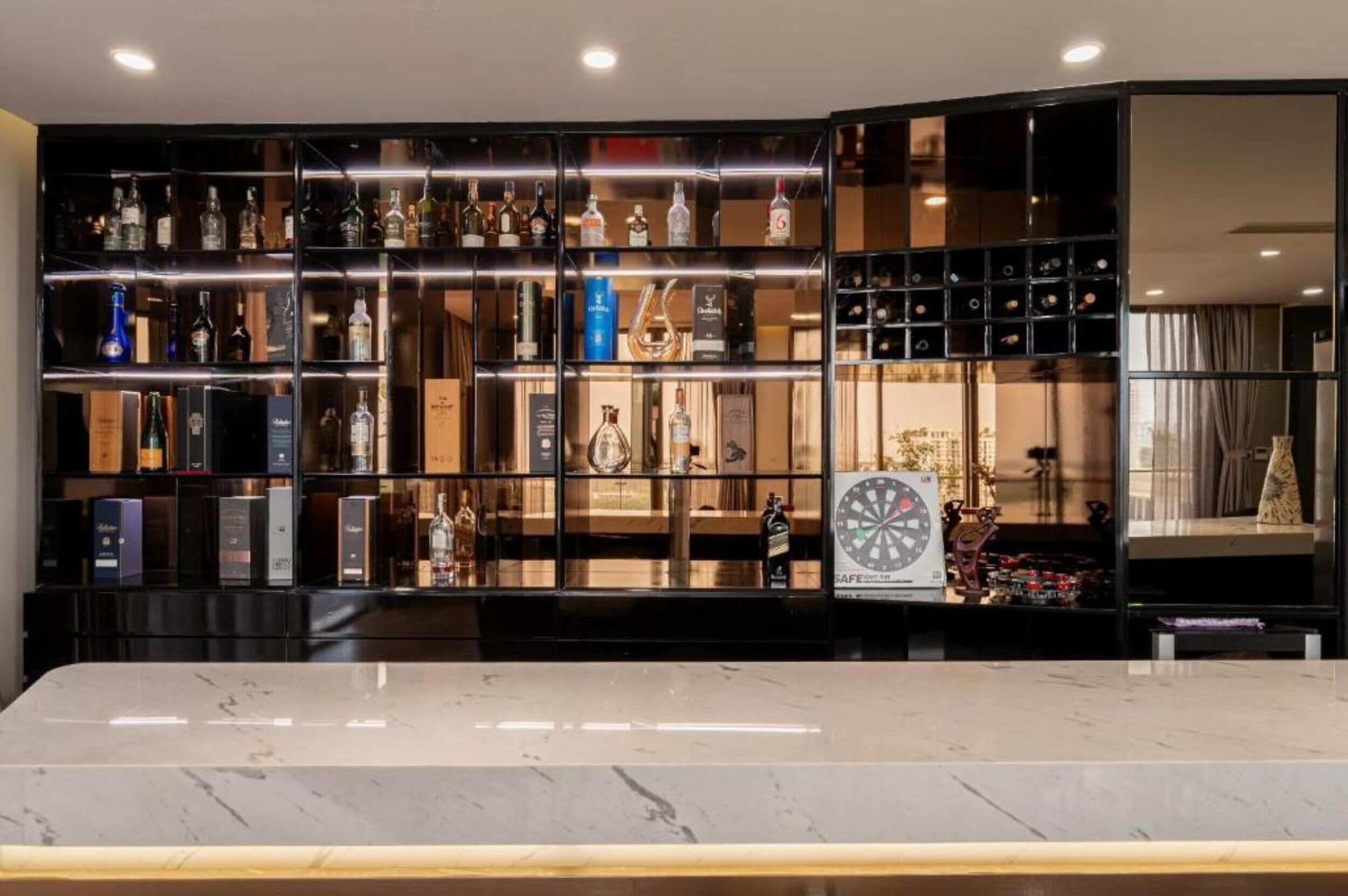 A bar area with shelves of liquor bottles, a dartboard, and a marble countertop.