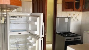 A kitchen with a refrigerator, stove, and wooden cabinets. - Place to stay in Nairobi (Nairobi)