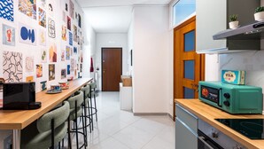 Una cocina moderna con microondas, tostadora y una pared decorada con varias obras de arte.