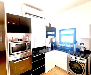 Eine kleine Küche mit Mikrowelle, Toaster und Waschmaschine.