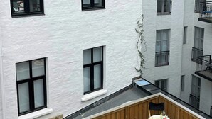 Eine Dachterrasse mit Holzboden, einem Tisch mit Stühlen und einer kleinen Sitzgelegenheit.