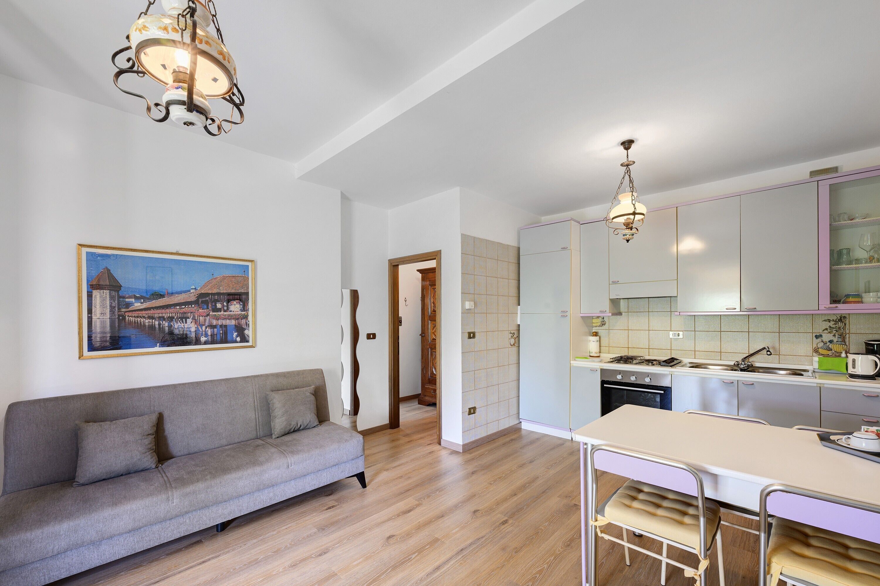 A modern kitchen with a dining area, a sofa, and a painting on the wall.