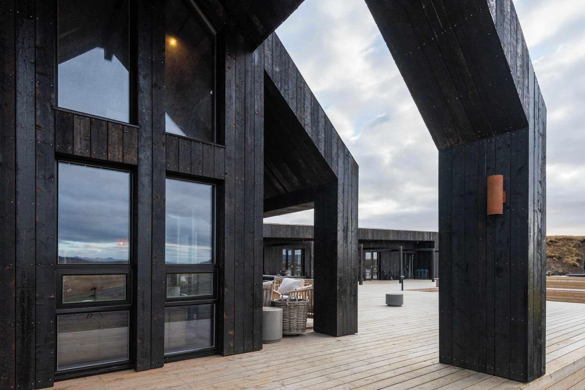 A modern building with large windows and a wooden deck.