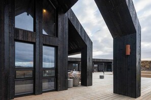 Een modern gebouw met grote ramen en een houten terras.