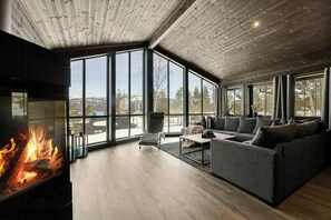 Una sala de estar moderna con chimenea, ventanas amplias y vistas al exterior.