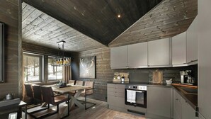 Una cocina moderna con horno integrado, cafetera y comedor con mesa y sillas de madera.
