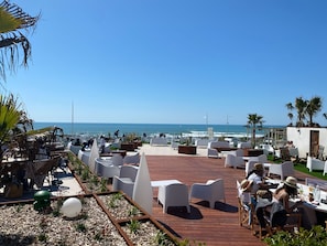 A terrace with white chairs and tables, overlooking the ocean.