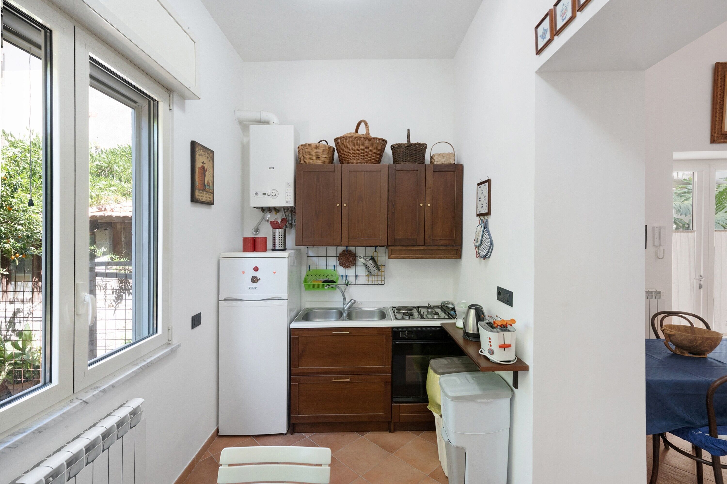 A compact kitchen with a refrigerator, stove, sink, and wooden cabinets.
