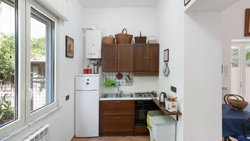 A compact kitchen with a refrigerator, stove, sink, and wooden cabinets.