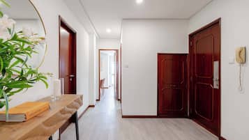 Un pasillo con un banco de madera, un florero con flores y un cuadro enmarcado.