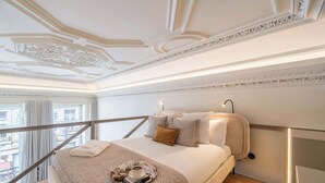 Ein Hotelzimmer mit Bett, Tablett mit Tasse und Buch, Nachttisch, Lampe und Balkonblick.