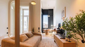Ein modernes Wohnzimmer mit einer Couch, einem Essbereich, einem Fernseher und einer Pflanze.