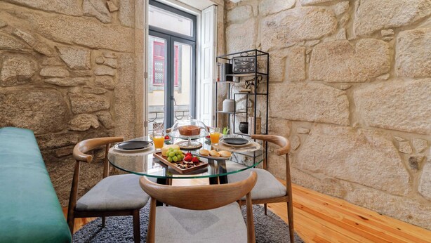 Una stanza con pareti in pietra, un tavolo da pranzo in vetro, sedie e una colazione servita.