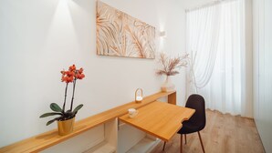 Een moderne kamer met een houten bureau, een witte muur, een groot abstract schilderij en een potplant.