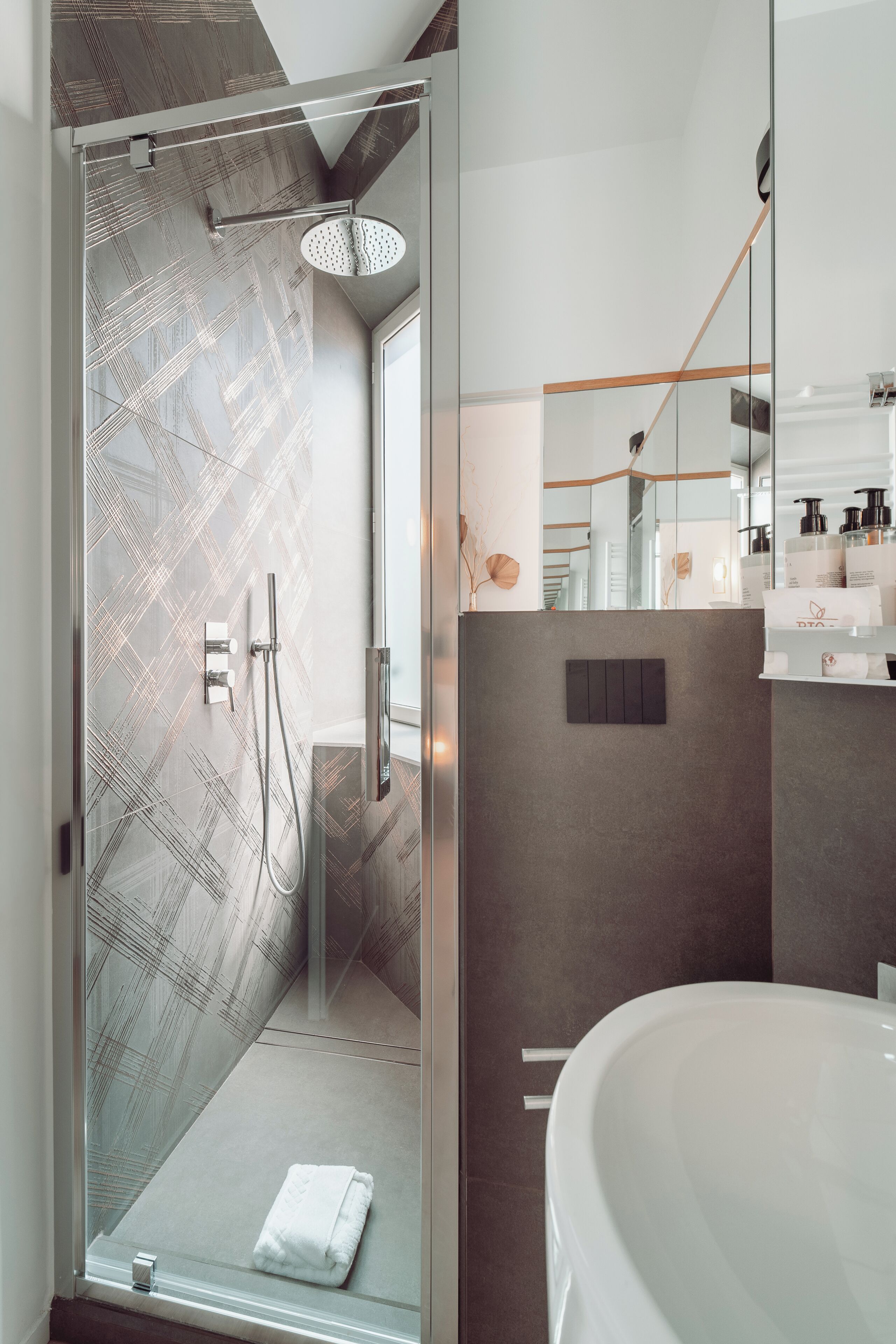 Un baño moderno con ducha de vidrio, una bañera blanca grande y un diseño minimalista.