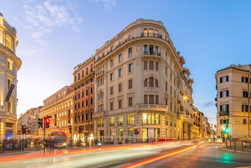 Un edificio storico dall'architettura classica, con più piani, ampie finestre e una facciata curva.
