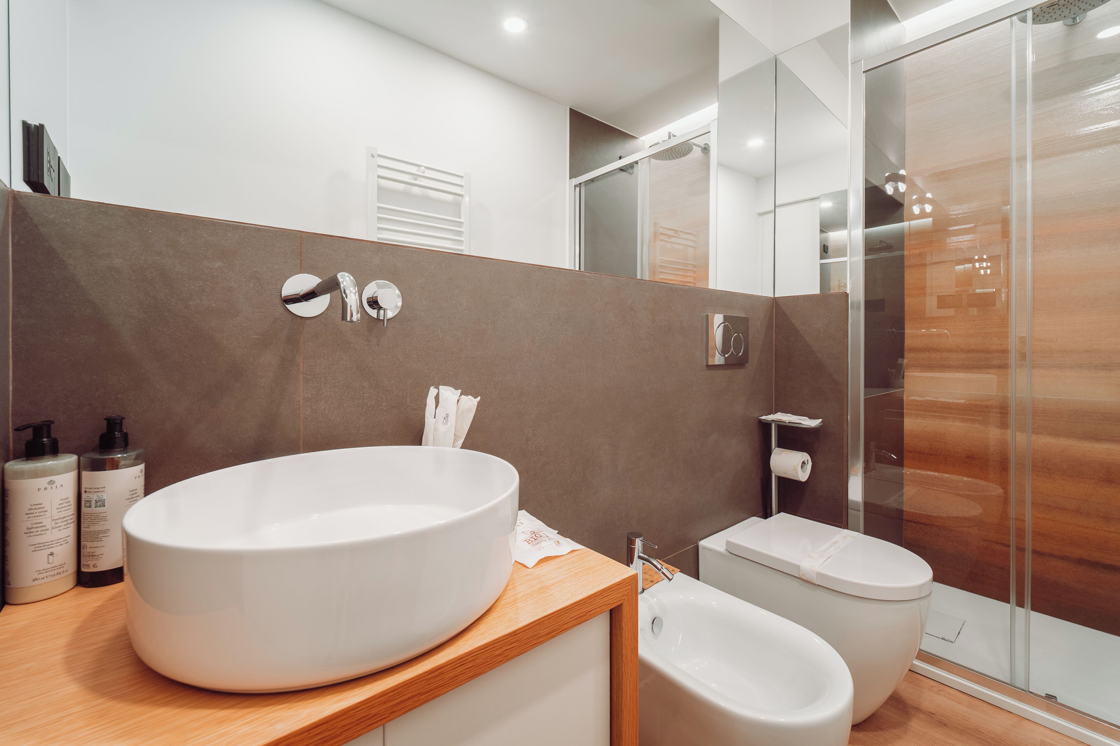 A modern bathroom with a large white sink, a toilet, and a glass shower enclosure.